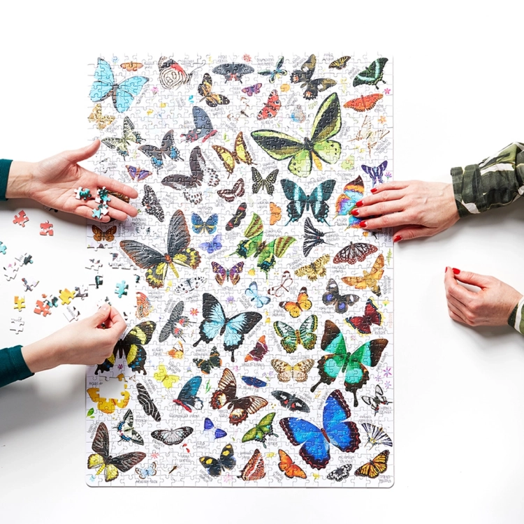 Dwie osoby układają puzzle Puzzlove Motyle CzuCzu na białym stole