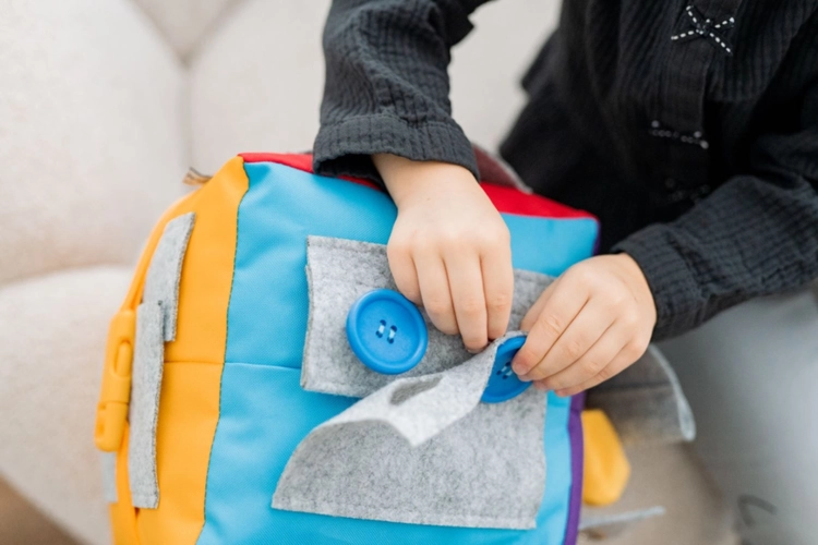 Dziecko bawiące się kostką manipulacyjną Surprise z kieszeniami – AKSON