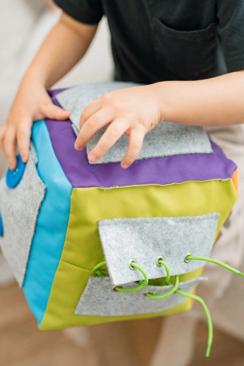 Dziecko bawiące się kostką manipulacyjną Surprise z kieszeniami – AKSON