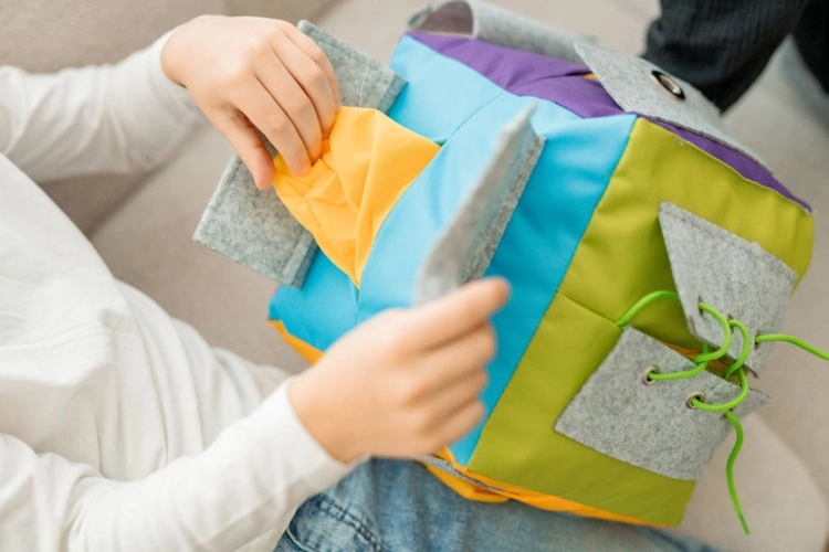 Dziecko bawiące się kostką manipulacyjną Surprise z kieszeniami – AKSON