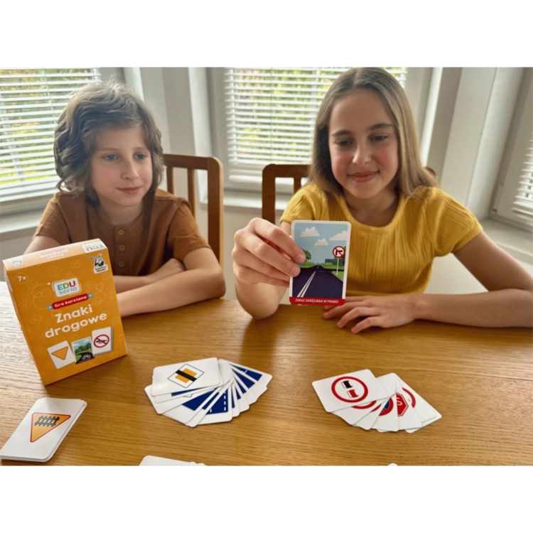 Dziewczynka pokazuje kartę z gry Znaki drogowe Kapitan Nauka 6+.