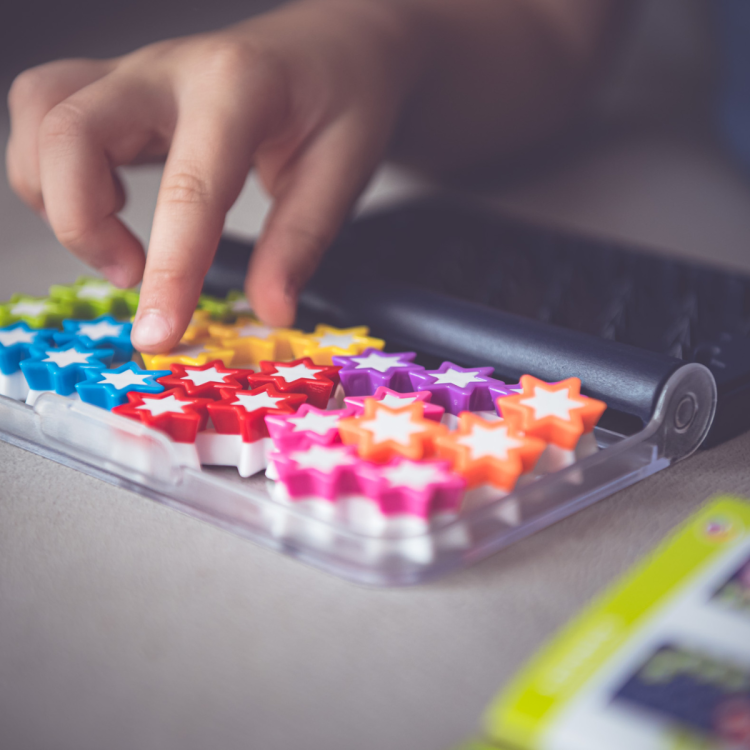 dziecko układa kolorowe gwiazdki w pudełku gry IQ Stars Smart Games