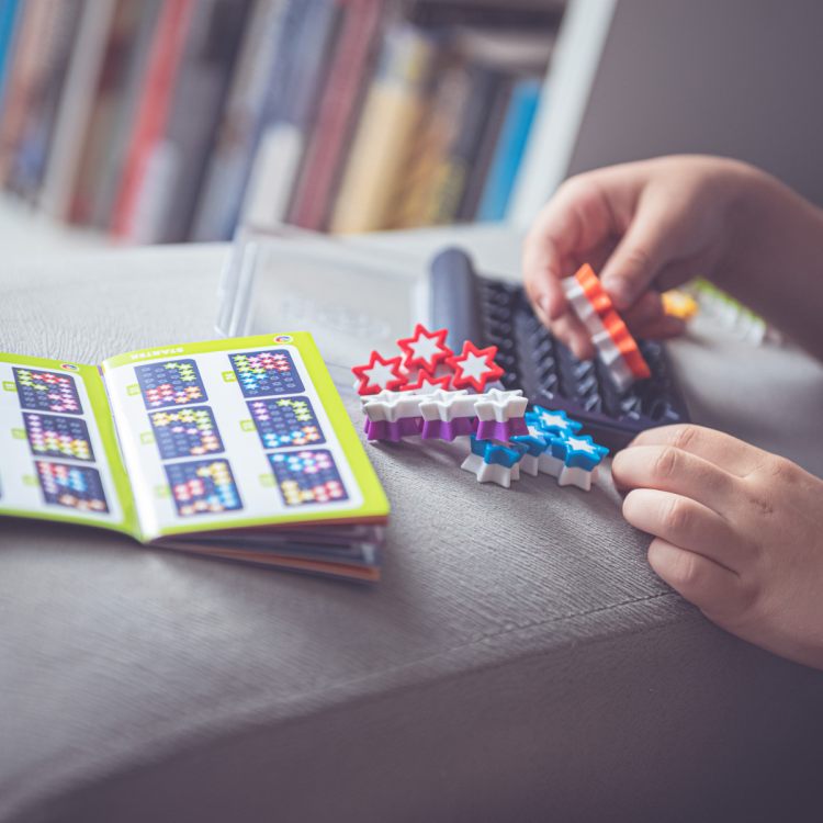 dziecko układa elementy gry IQ Stars Smart Games obok książeczki z zadaniami