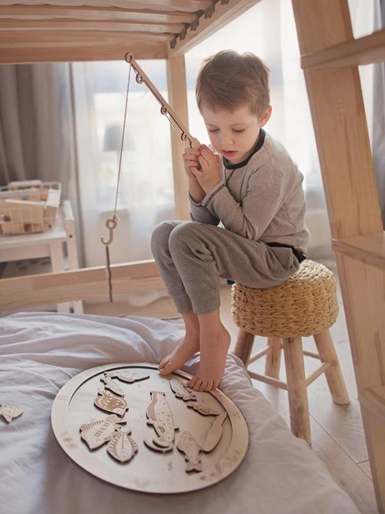 Dziecko łowi drewniane rybki w grze zręcznościowej Stuka Puka