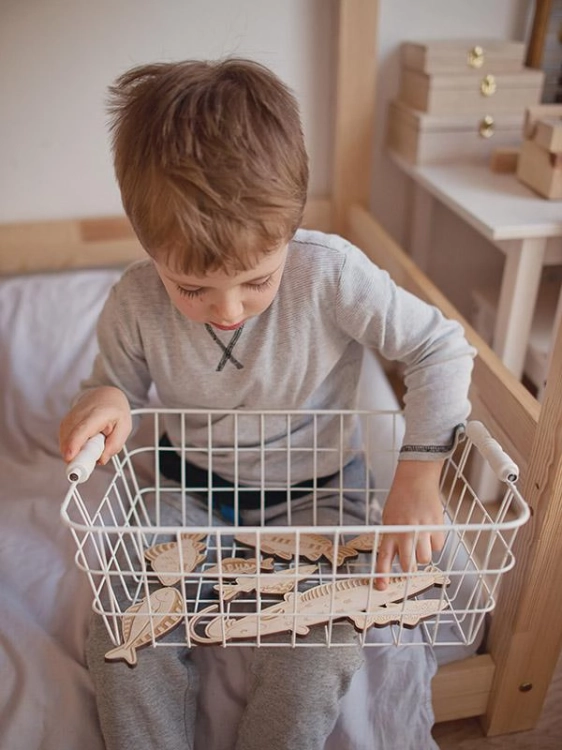 Chłopiec trzyma kosz z drewnianymi rybkami – gra zręcznościowa Stuka Puka