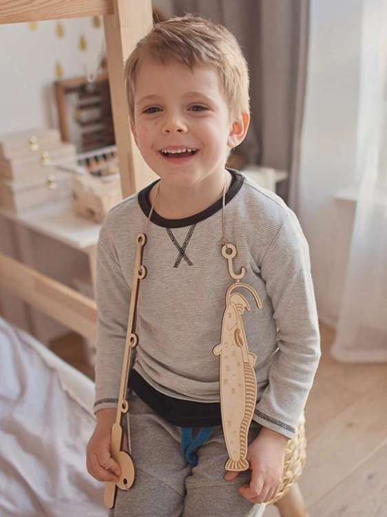 Chłopiec prezentuje drewnianą rybkę na wędce – gra Stuka Puka