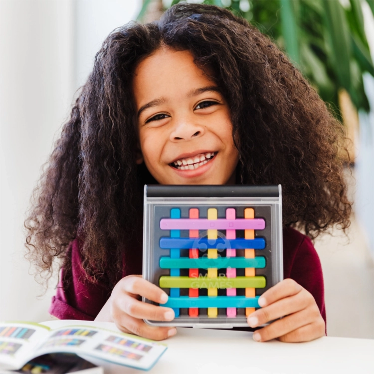 Uśmiechnięte dziecko trzyma planszę z kolorowymi patyczkami IQ Stixx.