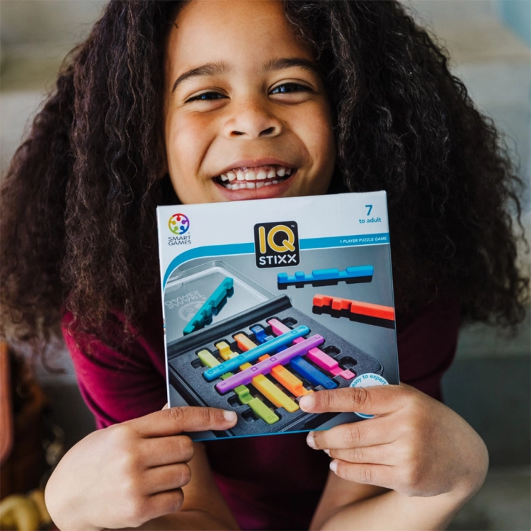 Dziewczynka pokazuje opakowanie gry IQ Stixx od Smart Games.