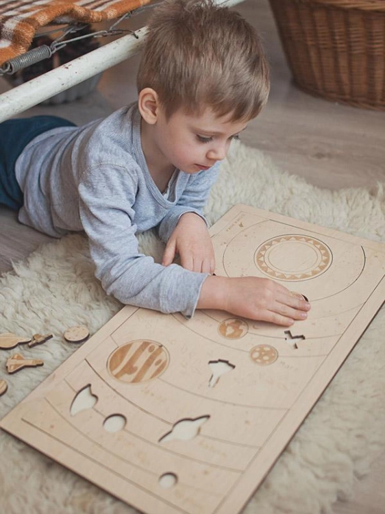 Dziecko układa drewniane puzzle z planetami Układu Słonecznego Sounds Wood