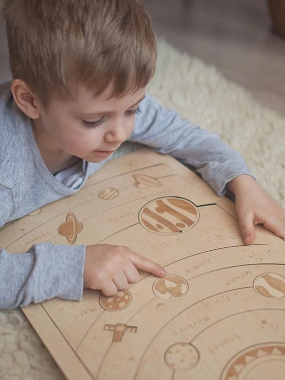 Dziecko wskazuje planetę na planszy Układu Słonecznego – puzzle drewniane