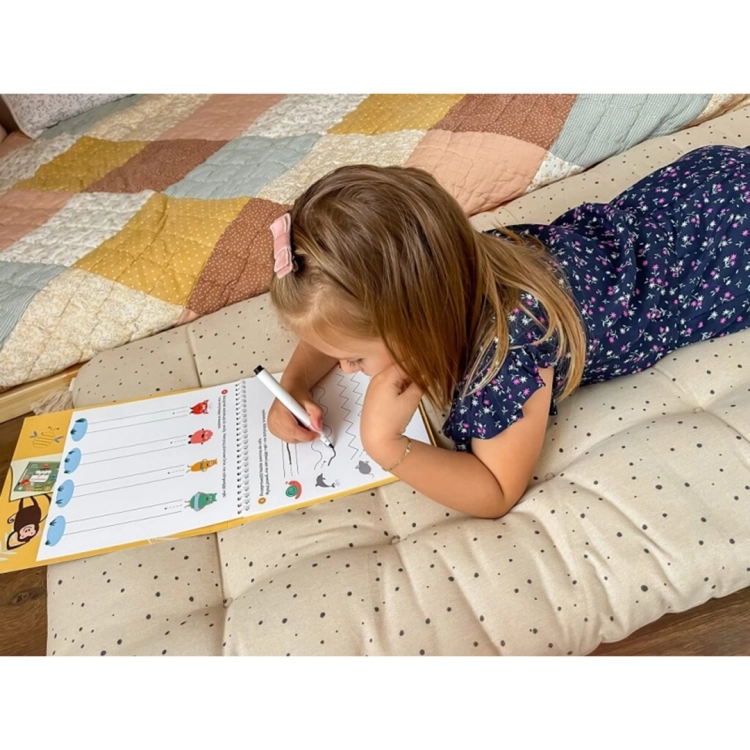 Dziewczynka rysująca w książeczce edukacyjnej Bazgraki wśród zwierząt Kapitan Nauka