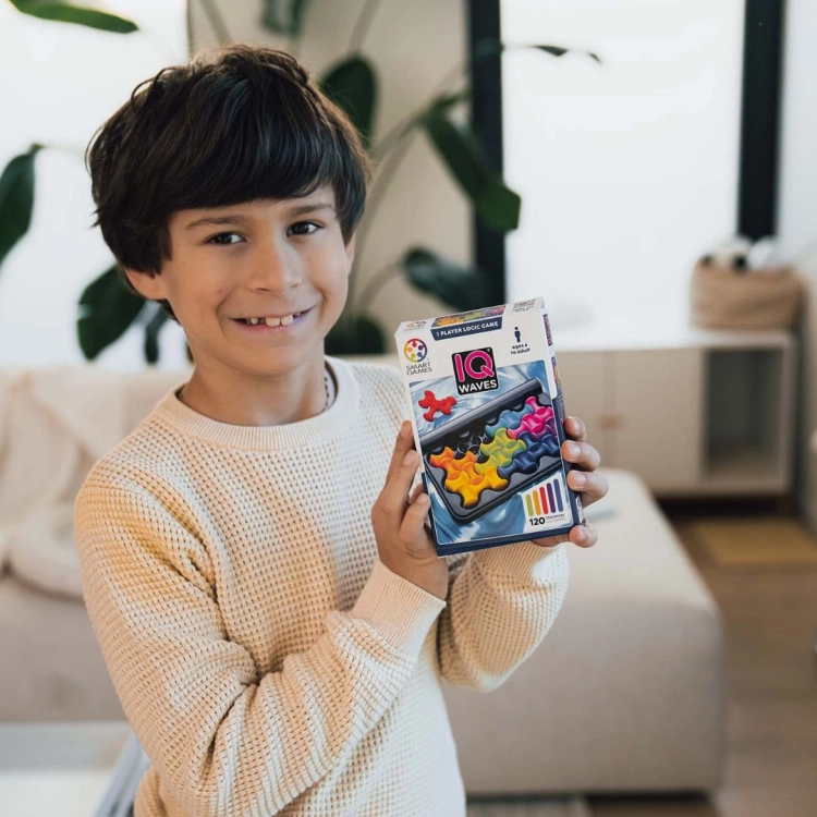 Chłopiec prezentujący pudełko gry IQ Waves od Smart Games
