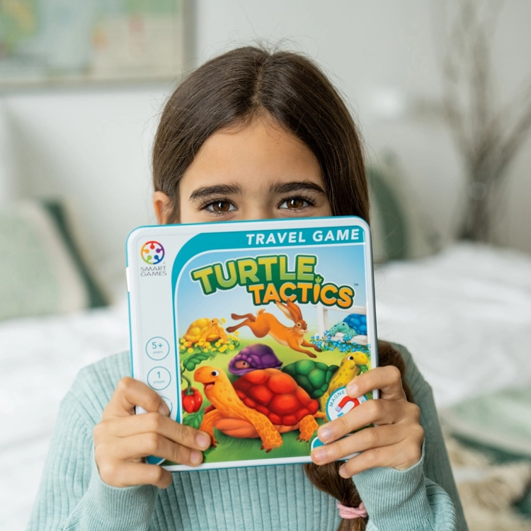 Dziewczynka trzyma grę Żółwim Tempem Smart Games w wersji Turtle Tactics