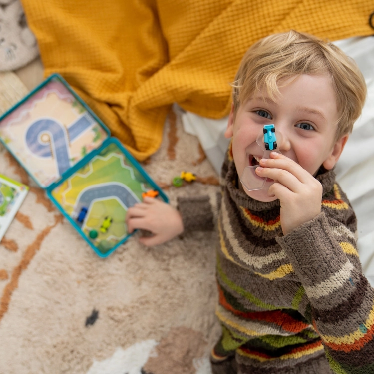 Chłopiec pokazuje bolid z gry Wyścigłówki i śmieje się do obiektywu