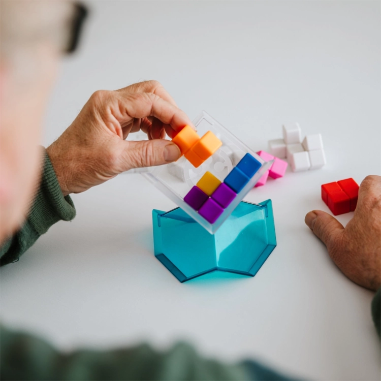 Starsza osoba układa klocki w grze Kubik – Smart Games 7+