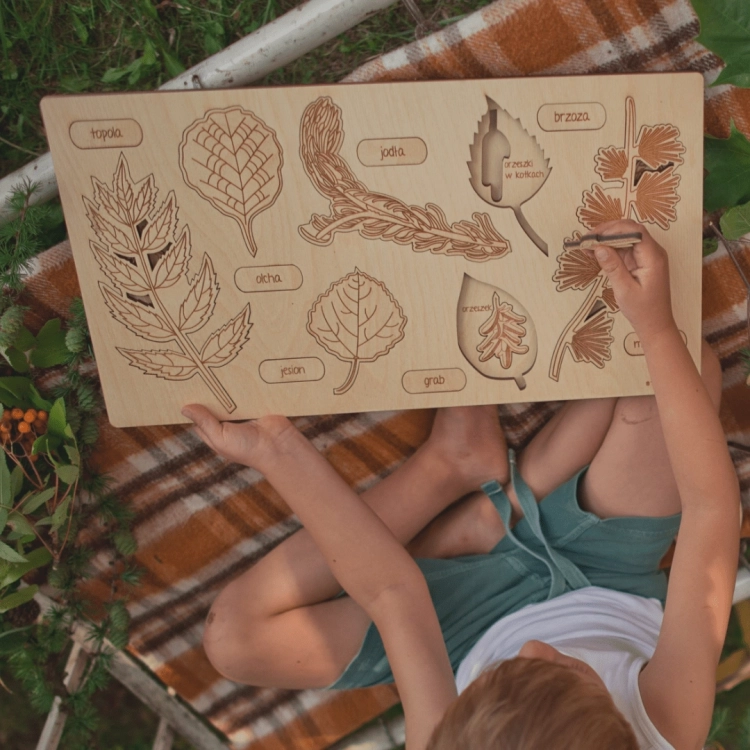 Widok z góry: dziecko układa puzzle edukacyjne z liśćmi drzew na planszy Sounds Wood