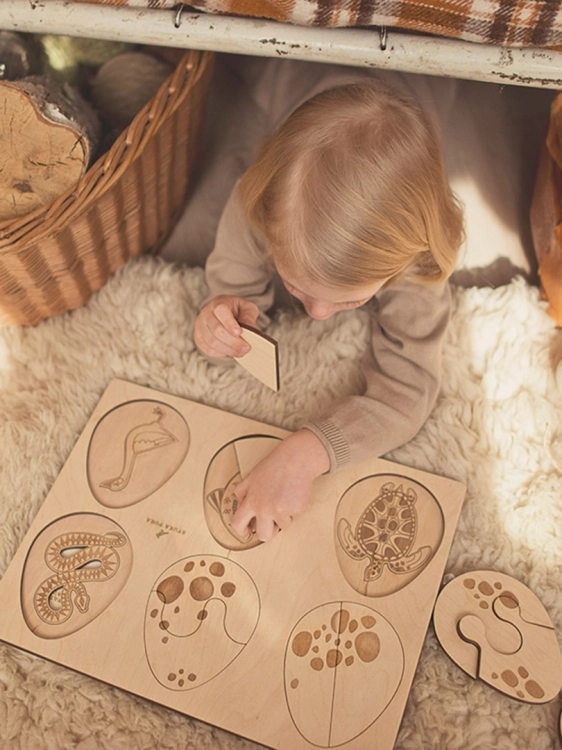 Dziecko układa puzzle przedstawiające zwierzęta wykluwające się z jajek.