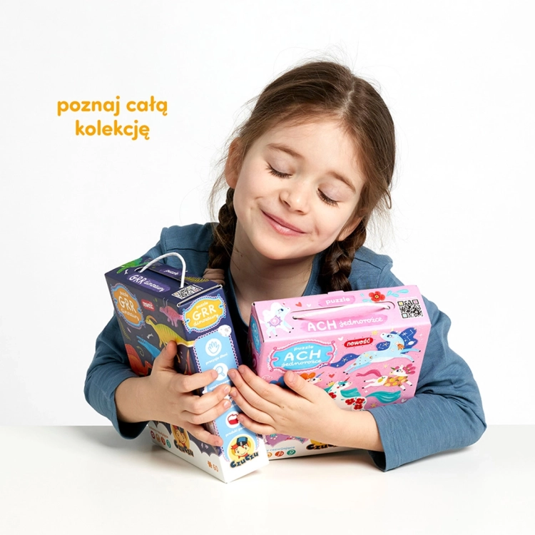 ziewczynka przytula pudełka puzzli Grr Dinozaury i Ach Jednorożce CzuCzu