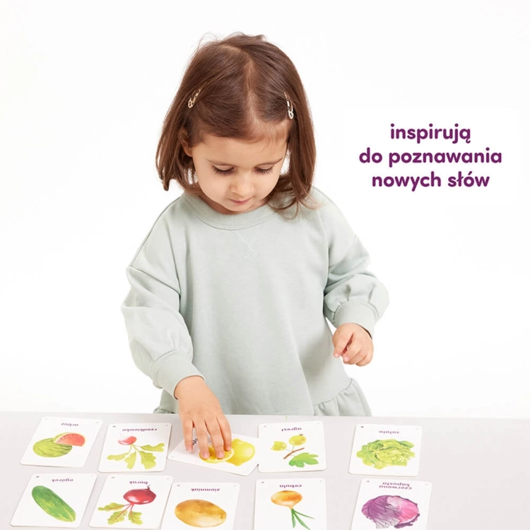 Dziewczynka układa karty CzuCzu z warzywami i owocami na stole