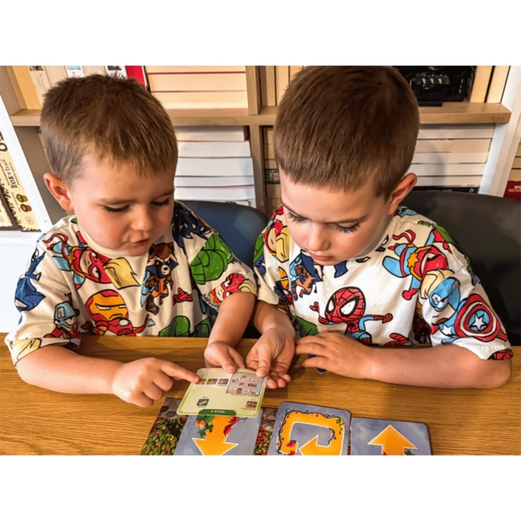 Chłopcy analizują kartę misji z gry edukacyjnej Zakodowany zamek