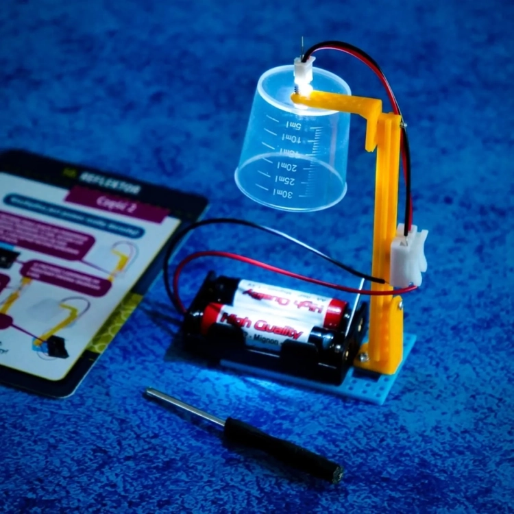 Eksperyment z prądem – podłączony kubek z diodą LED i bateriami