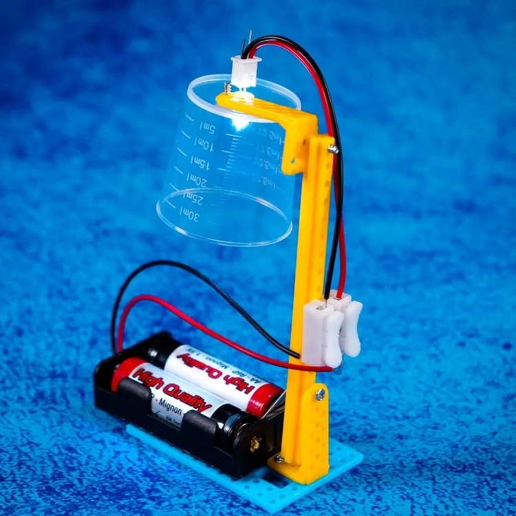 Eksperyment z prądem – podłączony kubek z diodą LED i bateriami