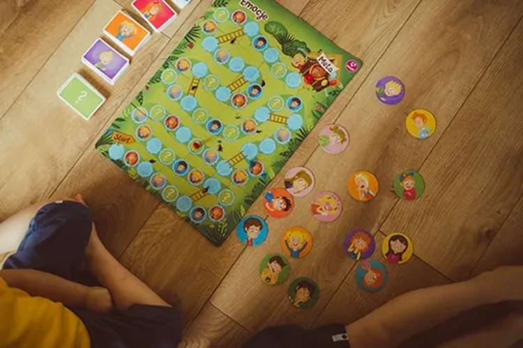 Dziecko grające w grę planszową Emocje Kukuryku – widok planszy i kolorowych żetonów