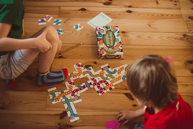 Dzieci grające w grę planszową Zakręcone robale Kukuryku na drewnianej podłodze