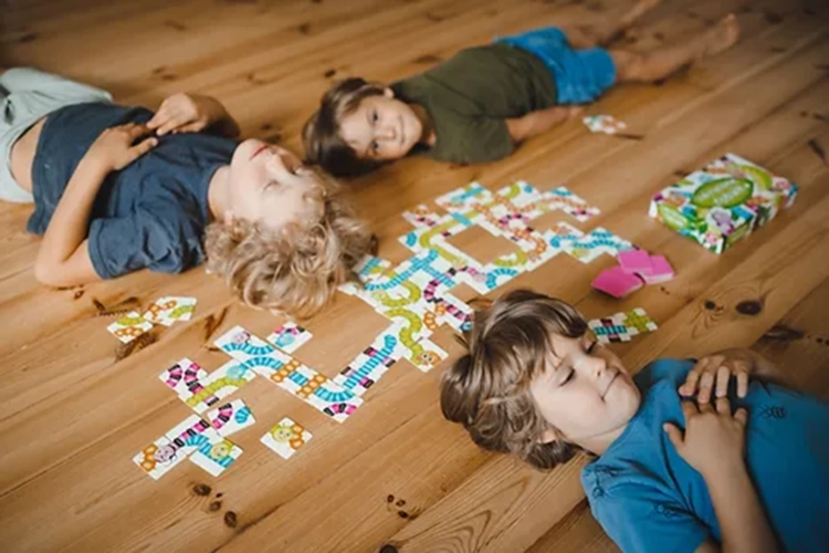 Trójka dzieci bawi się grą Zakręcone robale Kukuryku układając robale z kart