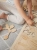 Ręka dziecka wkładająca warzywo do puzzli drewnianych Sounds Wood