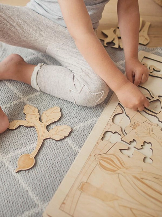 Ręka dziecka wkładająca warzywo do puzzli drewnianych Sounds Wood