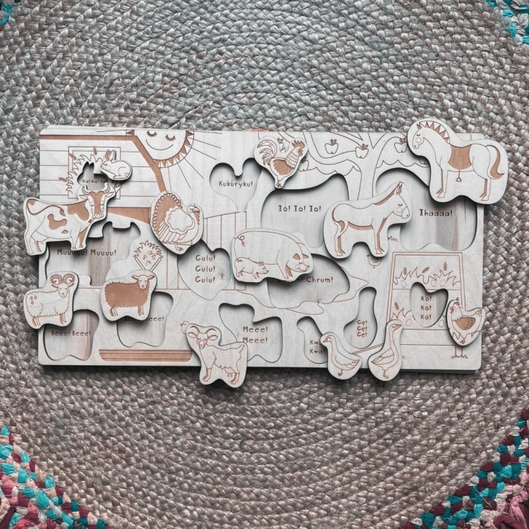 Rozłożone drewniane puzzle przedstawiające zwierzęta z farmy i ich polskie nazwy dźwiękonaśladowcze.