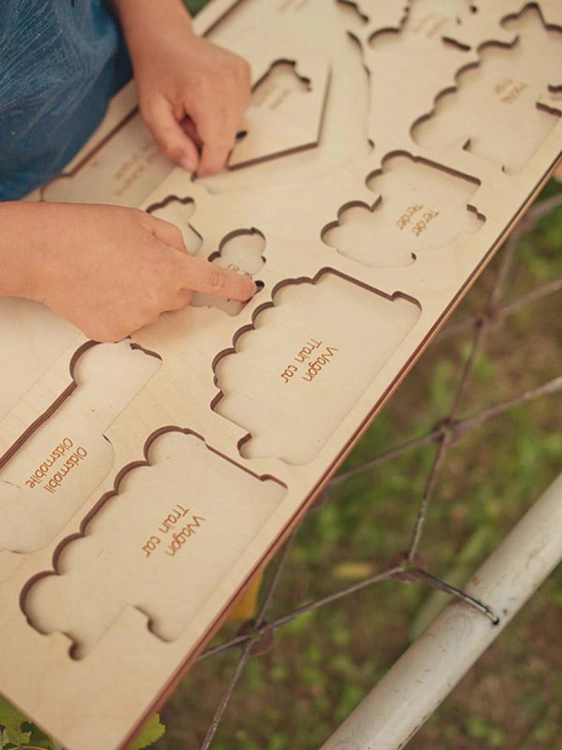 Detal drewnianej układanki z nazwami pojazdów, dziecko dopasowuje elementy.