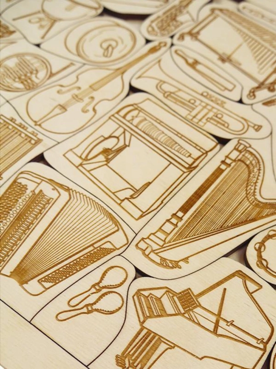 Różnorodne drewniane elementy puzzli w kształcie instrumentów muzycznych.