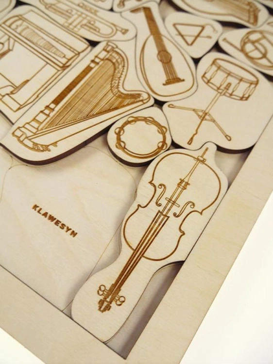 Powiększenie drewnianego elementu puzzli przedstawiającego wiolonczelę i fragment klawesynu.