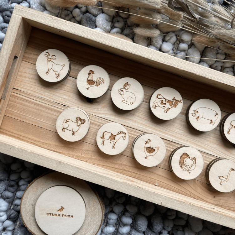 Zbliżenie na drewniane krążki gry memory Sounds Wood z ilustracjami zwierząt w drewnianym organizerze.