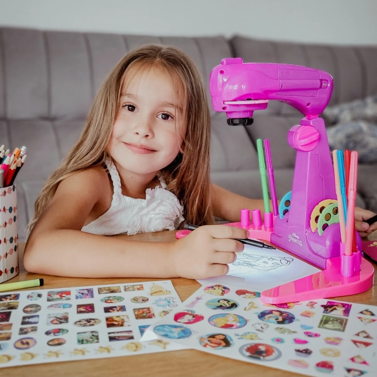 Uśmiechnięta dziewczynka rysuje wzory z projektora Disney Princess