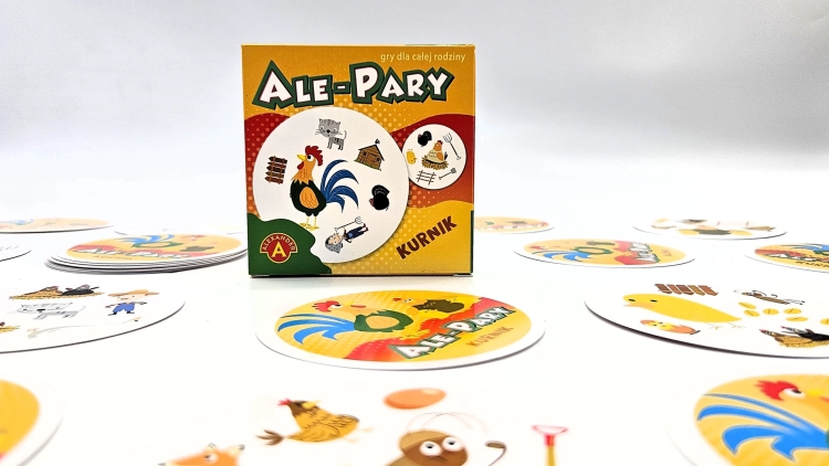 Pudełko gry karcianej Ale Pary Kurnik na tle rozłożonych kart, z widocznym kogutem na okładce.