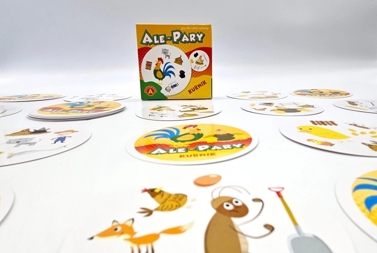 Karty do gry Ale Pary Kurnik rozłożone wokół pudełka, ukazujące różnorodne grafiki zwierząt i przedmiotów z farmy.