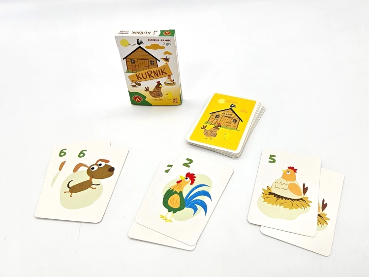 Pudełko gry karcianej Piotruś Pamięć Kurnik obok stosu zakrytych kart i kilku rozłożonych kart z ilustracjami psa, koguta i kury w gnieździe.