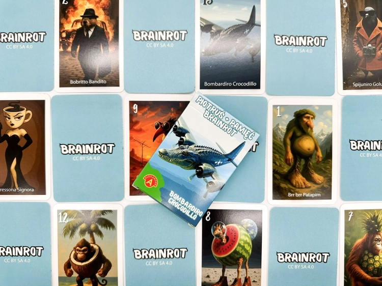 Pudełko gry Piotruś Brainrot Bombardiro Crocodillo na tle rozłożonych kart z różnorodnymi, abstrakcyjnymi postaciami.