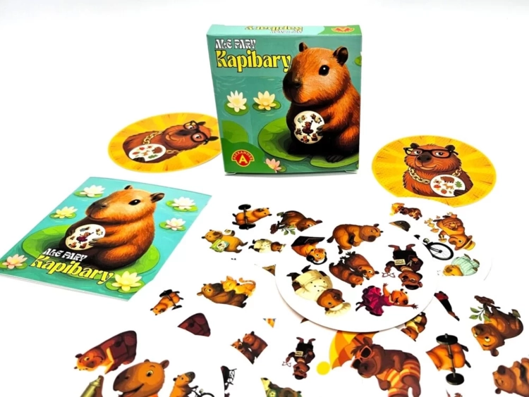 Pudełko gry "Ale Pary Kapibary" obok instrukcji i rozłożonych okrągłych kart z licznymi ilustracjami kapibar.