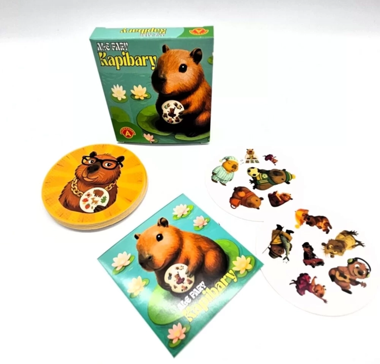 Pudełko gry "Ale Pary Kapibary", stos okrągłych kart oraz pojedyncza karta z kapibarą w okularach.