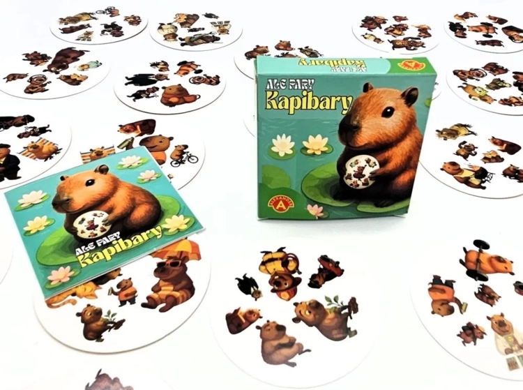 Pudełko gry "Ale Pary Kapibary", osobna karta i stos kart, wszystko z ilustracjami kapibar.