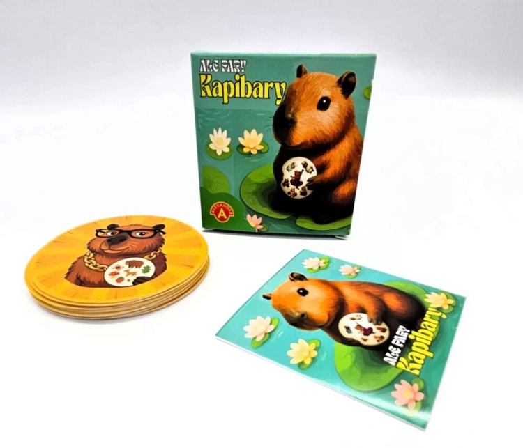 Pudełko gry "Ale Pary Kapibary" obok stosu okrągłych kart i pojedynczej karty z ilustracją kapibary.