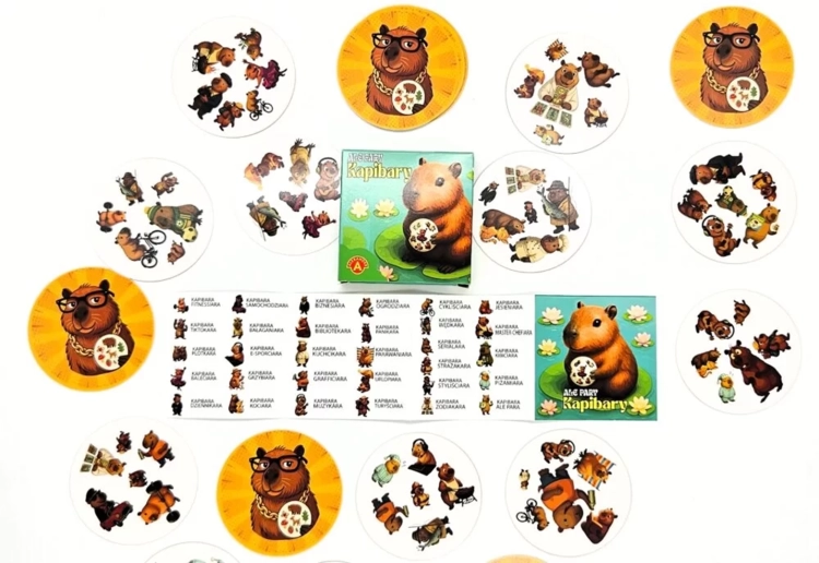 Pudełko gry "Ale Pary Kapibary" otoczone okrągłymi kartami i instrukcją, wszystko z motywem kapibar.