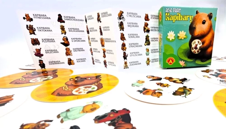 Pudełko gry "Ale Pary Kapibary" z instrukcją i rozrzuconymi okrągłymi kartami z kapibarami.