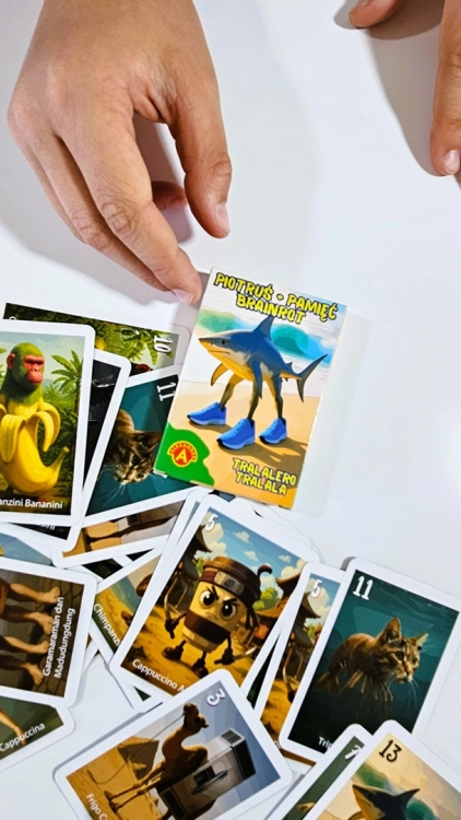 Ręce graczy dobierają karty z rozsypanego stosu gry Piotruś Brainrot.