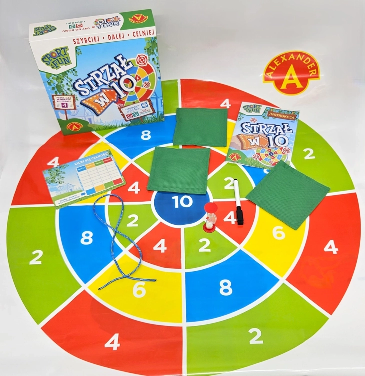 Rozłożona mata do gry "Strzał w 10" na białym tle, otoczona akcesoriami.