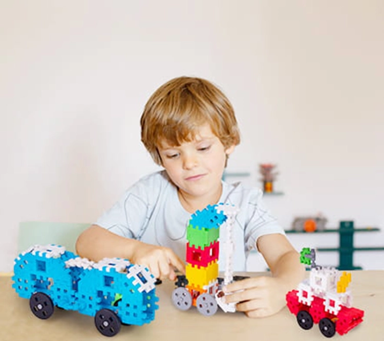 Chłopiec bawi się klockami Marioinex Mini Waffle Constructor, budując pojazdy.